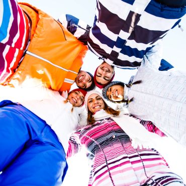 Cinco personas sonrientes vestidas con ropa de invierno.