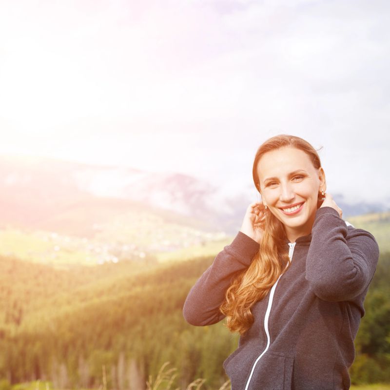 Outdoors portrait of young smiling woman in mountains with copy space