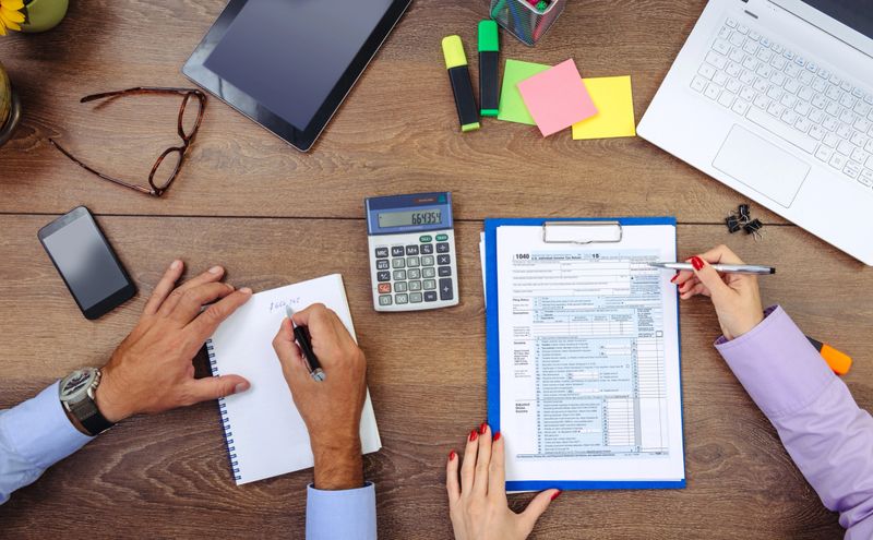 Two professionals in office, one young female and one male, in formal clothing, dealing with finance, financial issues, investments, and market analysis. Image taken from above - overhead image, representing teamwork and collaboration, brainstorming and progressive innovative work. Image taken with Nikon D800 and 50mmm or 24-70 professional Nikon Lens.