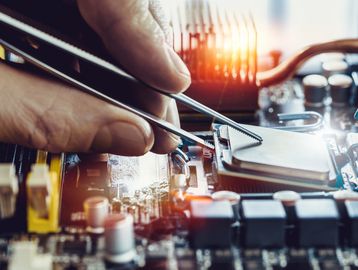 Close-up of hands installing a CPU on a motherboard with tweezers.