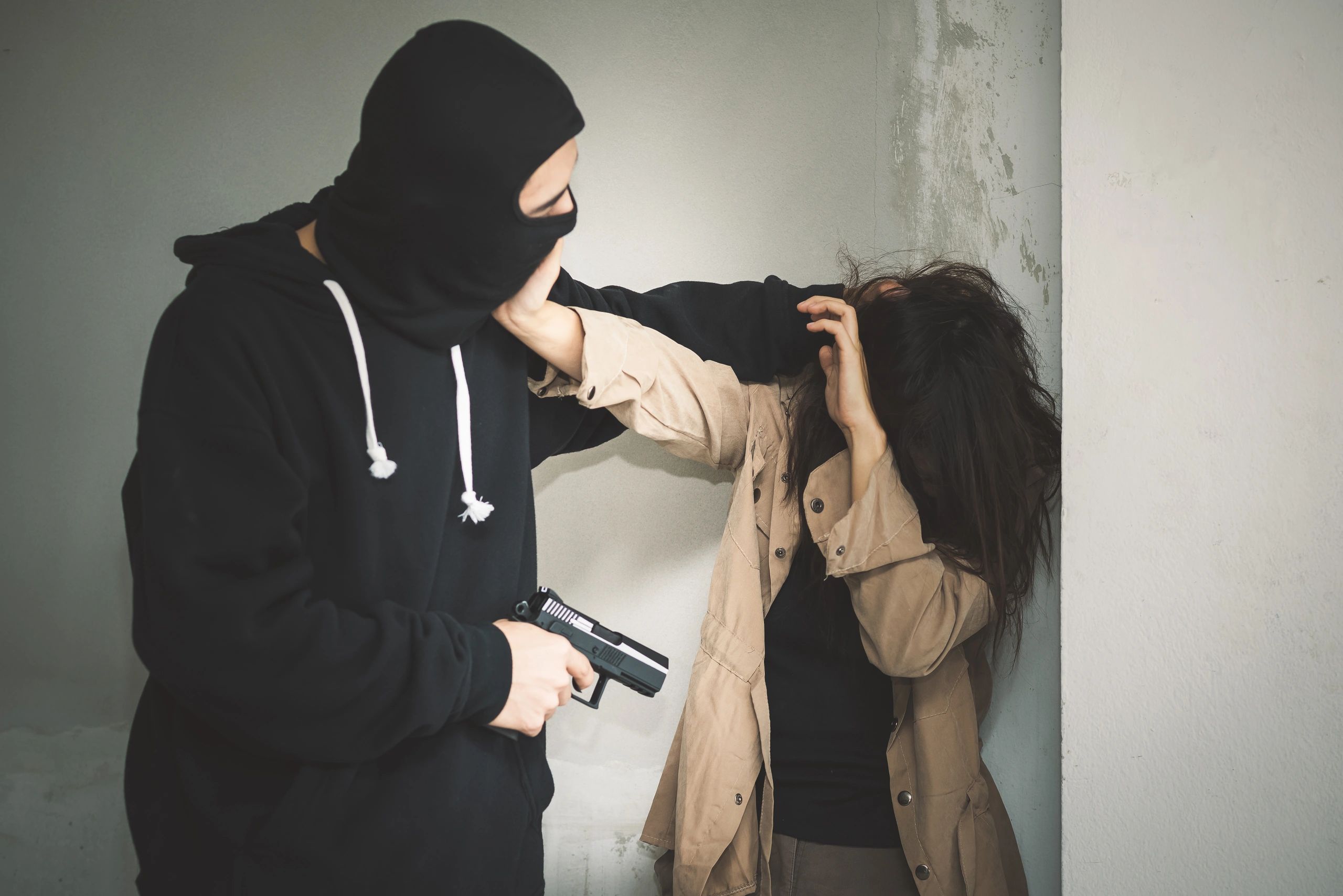 Masked man threatening woman with a gun in a tense confrontation.