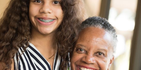 Smiling young girl with braces and older woman with short hair.