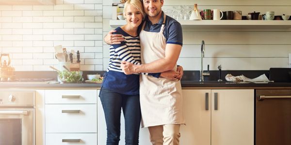Happy couple embracing in a modern kitchen with warm lighting.