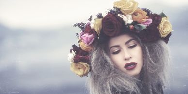 Woman with voluminous gray hair wearing a vibrant floral crown.