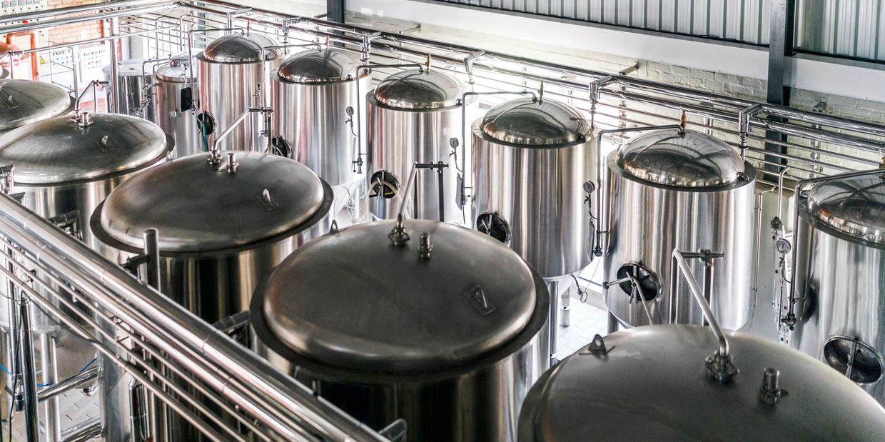 Rows of large stainless steel brewing tanks in a brewery.
