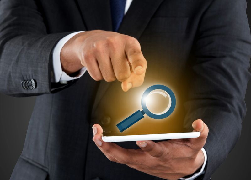 Businessman holding digital tablet and touching magnifying glass icon on touch screen