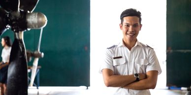 Confident young man in pilot uniform smiling with arms crossed.