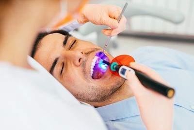 Dentist using a curing light on a patient's teeth during treatment.