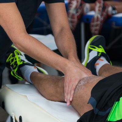 Physical therapist massages athlete's knee during treatment session.