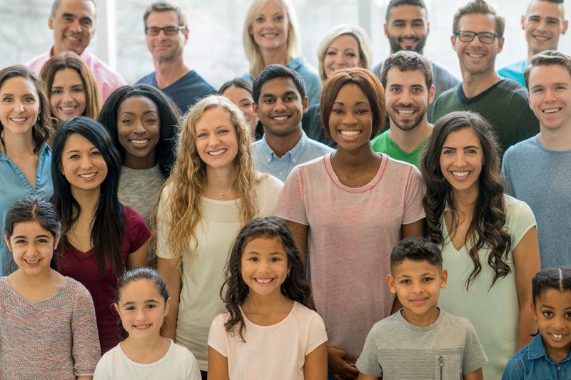 A large, multi-ethnic group of people gather together in an open space.