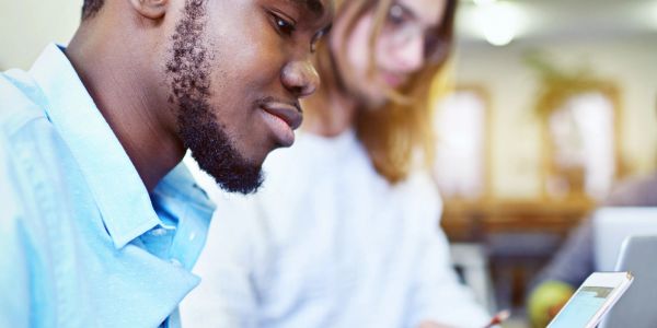 Two young men collaborating, focusing on a tablet screen in a casual setting.