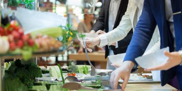 People serving food from a buffet line.