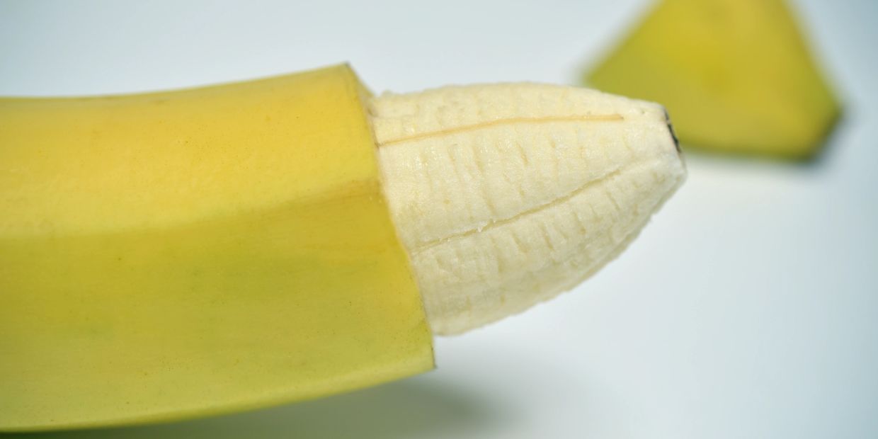 A partially peeled banana with the tip cut off.