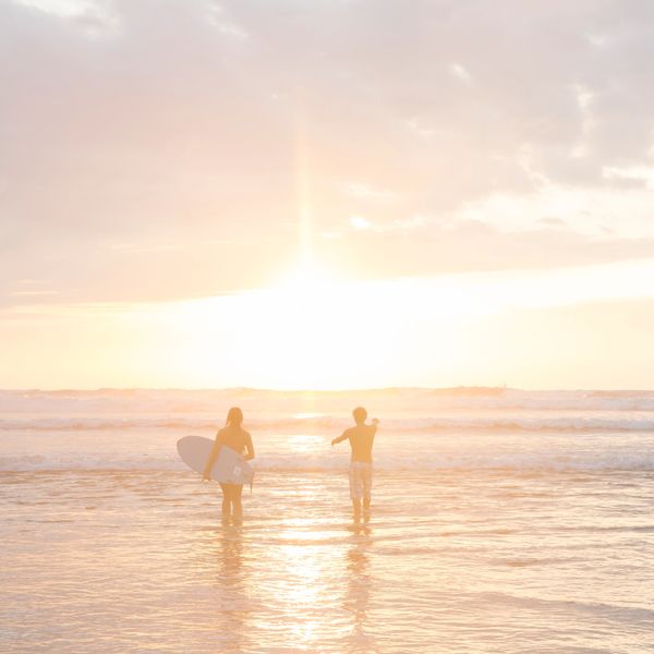 Two people enjoying a sunset surf at the beach.