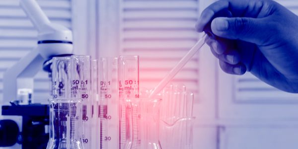 Scientist using a pipette with test tubes and microscope in a lab.
