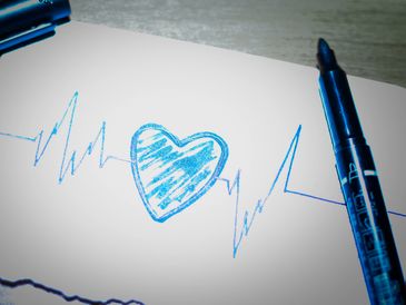 A heart beat with a heart shape in the middle drawn in blue ink on a white piece of paper.