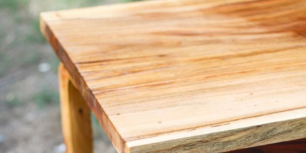 Close-up of a polished wooden table corner outdoors.