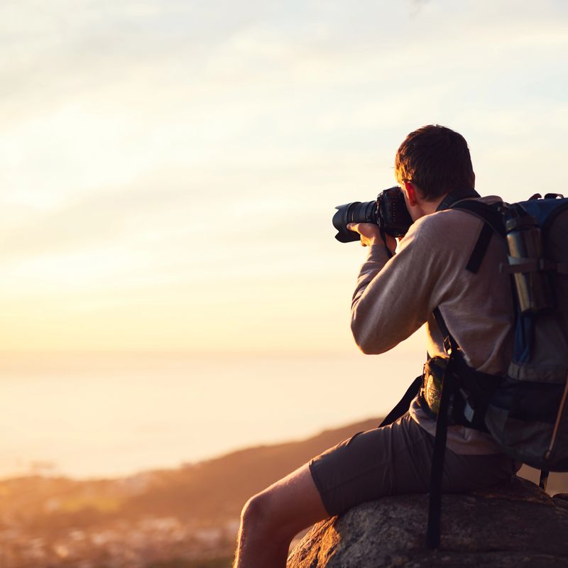 Shot of a young photographer taking a picture from the top of a mountain