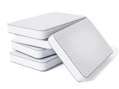 Stack of four white mattresses with one leaning.