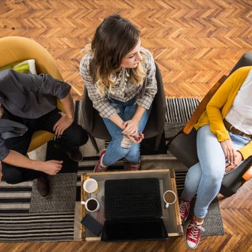 Three people sitting around a coffee table with laptops and coffee cups.