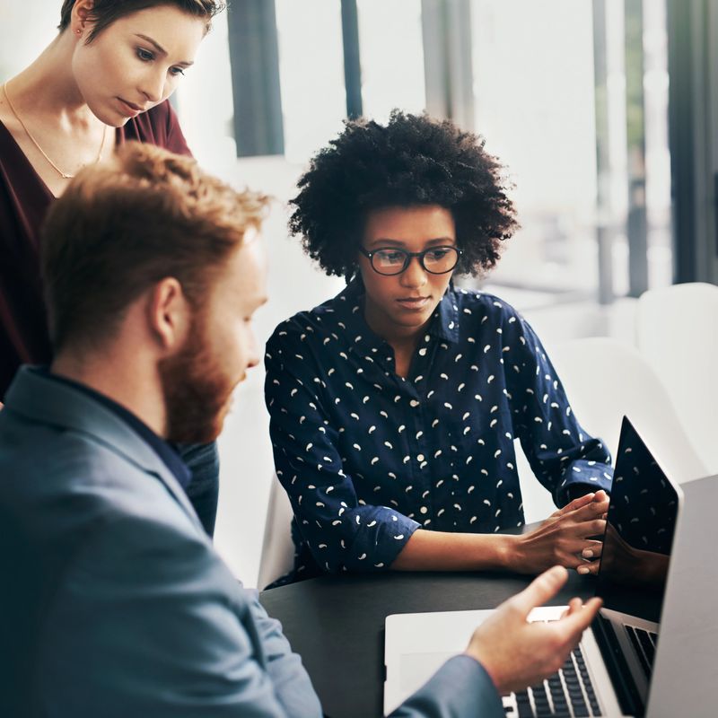 Shot of a group of colleagues using a laptop together at work