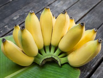 Racimo de plátanos maduros sobre una hoja verde.