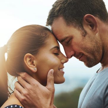 A couple sharing a tender moment, foreheads touching with smiles.