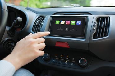 Person using touchscreen interface in a car dashboard for climate control and apps.