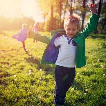 Children joyfully playing outside in the sunlight.