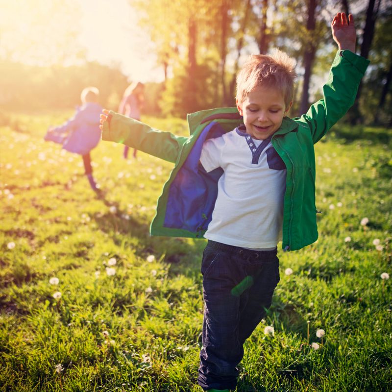 Little boys aged 6 and his brother and sister are enjoying spring walk. Kids are running on fresh spring grass on one of the first beautiful sunny days of spring.