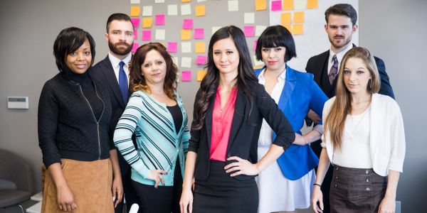 Seven professionals posing confidently in an office.