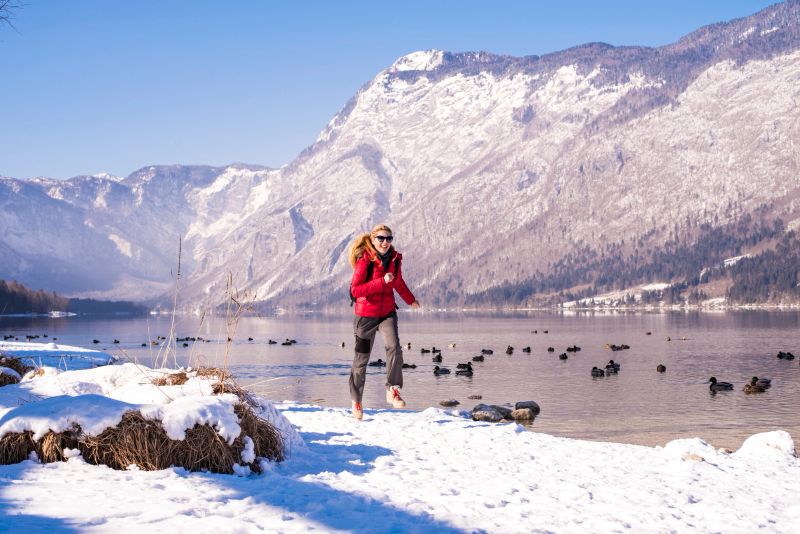 Smiling woman running along the lake in the mountains