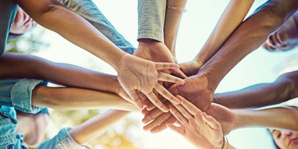 Diverse team putting hands in