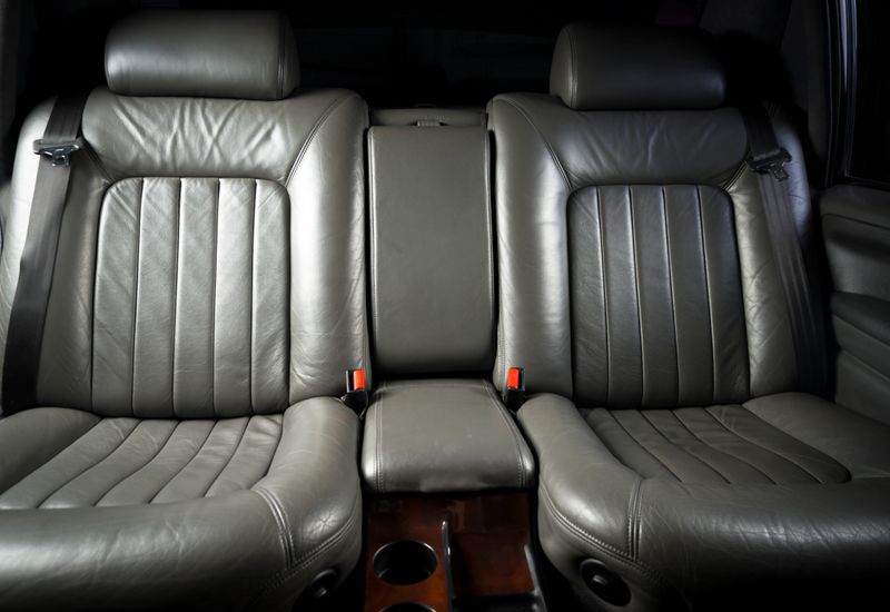 Back passenger seats in rertro luxury car, frontal view, black leather