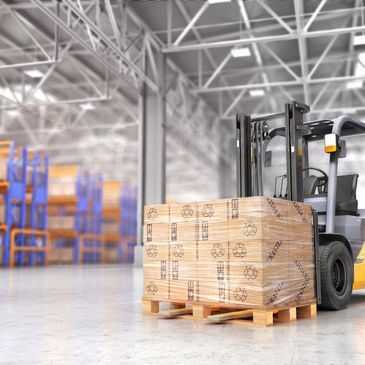 Forklift moving stacked boxes on a pallet inside a warehouse.