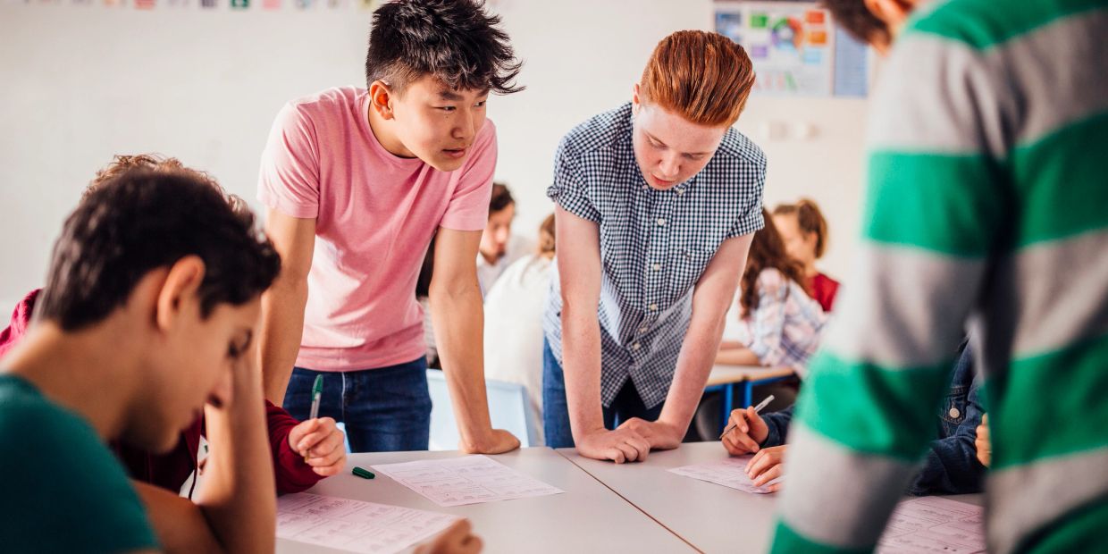 Teen students collaborate on a group assignment in a classroom setting.
