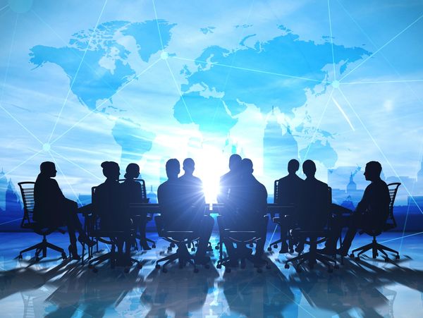 Silhouettes of business people in a meeting with a world map background.