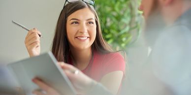 Young woman smiling while holding a pen in a conversation.