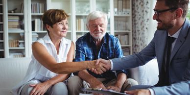 Elderly couple shaking hands with a professional in a cozy living room.