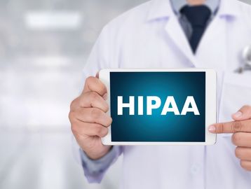 Doctor holding a tablet showing the word HIPAA.