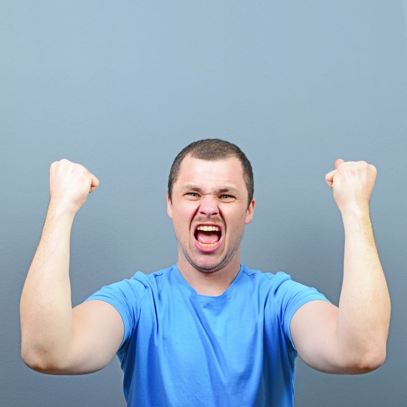 Portrait of ecstatic young man celebrating victory or win against gray background