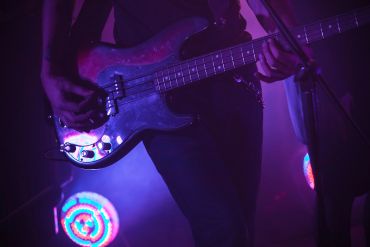 Young man passionately playing guitar and singing on stage.
