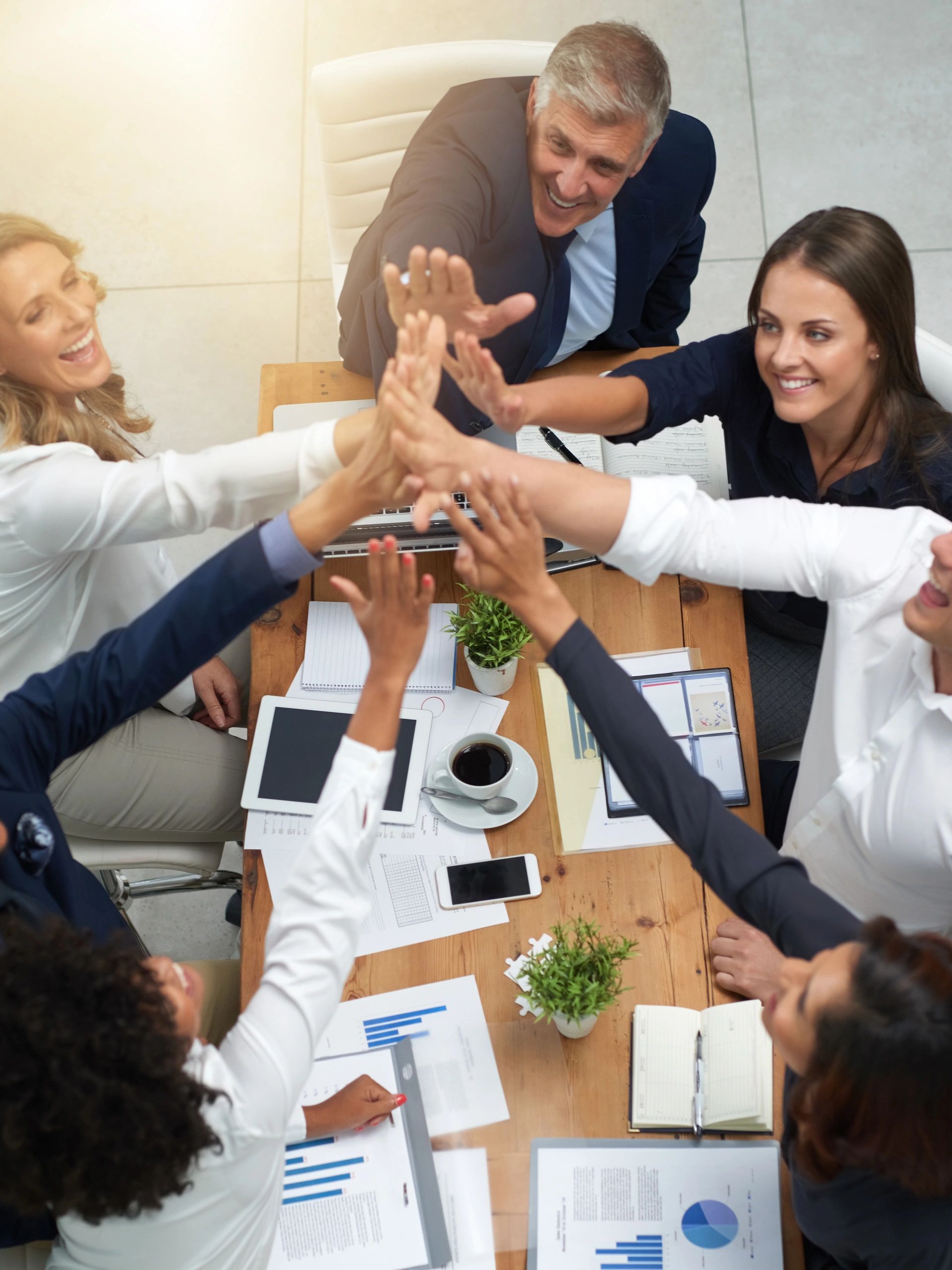 Team of professionals celebrating with a group high-five in a business setting.