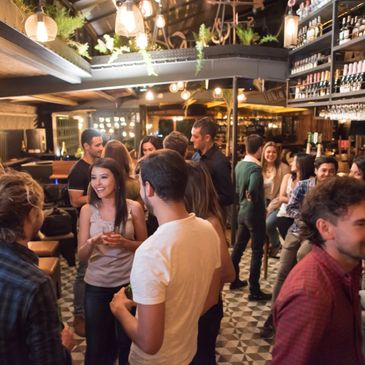 People socializing and enjoying drinks in a lively bar setting.