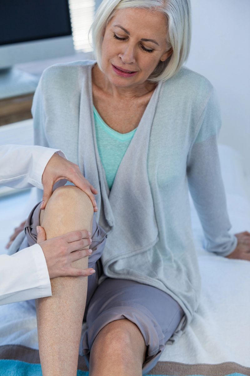 Doctor examining patient knee in clinic