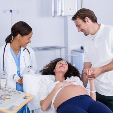 Pregnant woman receiving support from partner and medical staff.