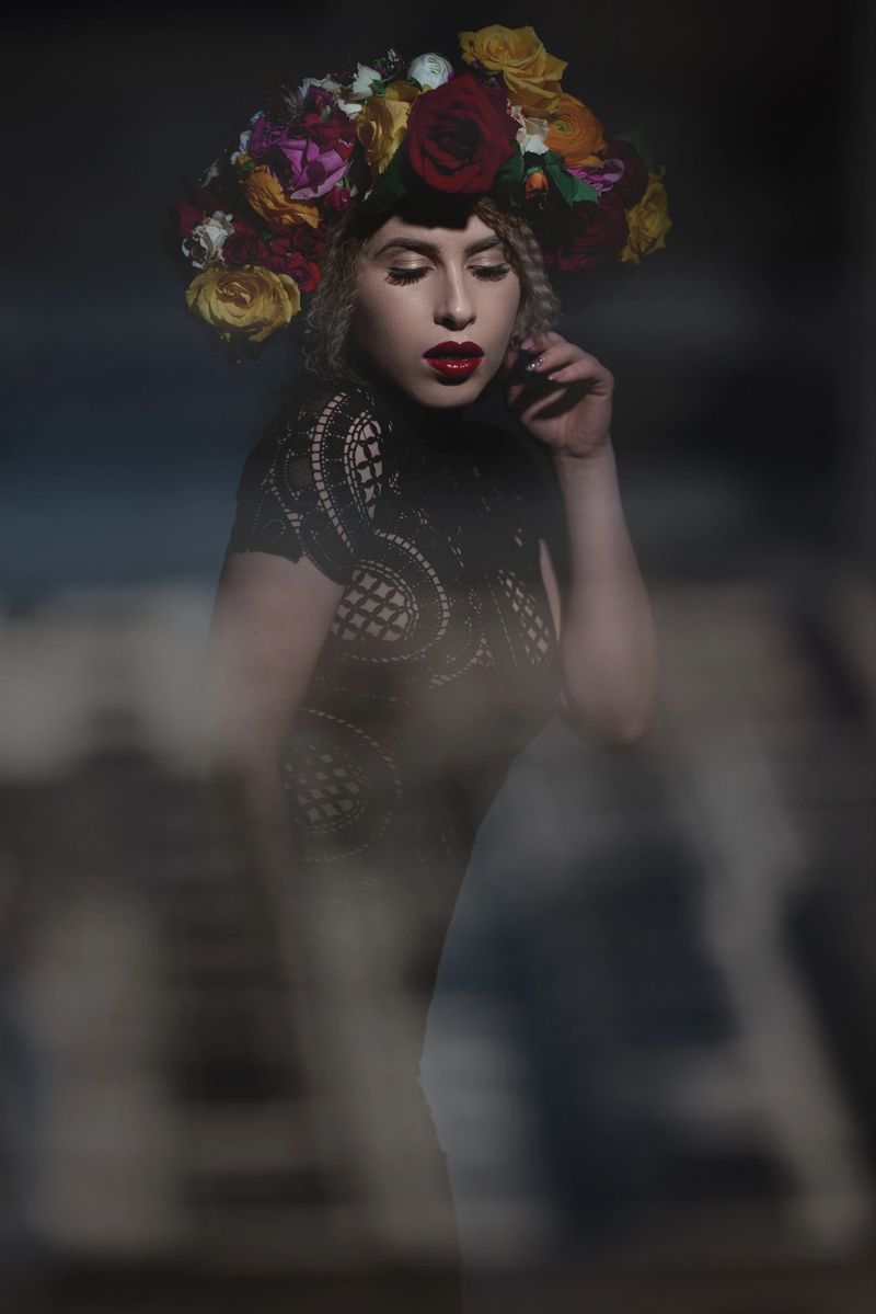 attractive fashion model wearing black lace dress and colorful flower garland and feeling seductive.