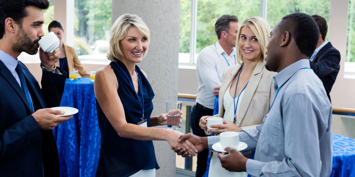 Business people networking and shaking hands during a coffee break.