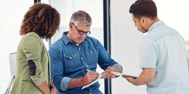 Three professionals collaborating over documents in a modern office.