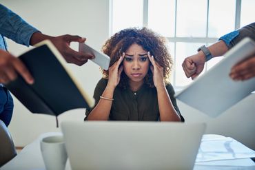 Stressed woman overwhelmed by multiple tasks at work.